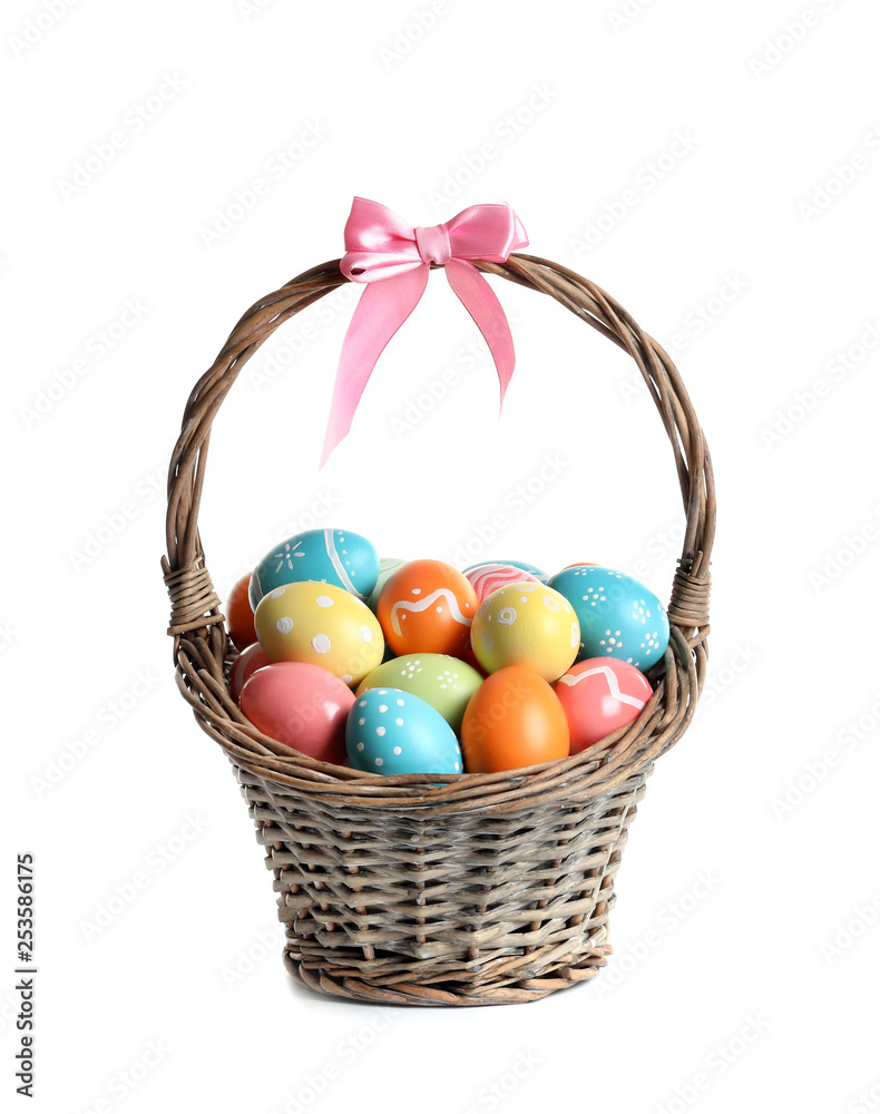Wicker basket with painted Easter eggs on white background