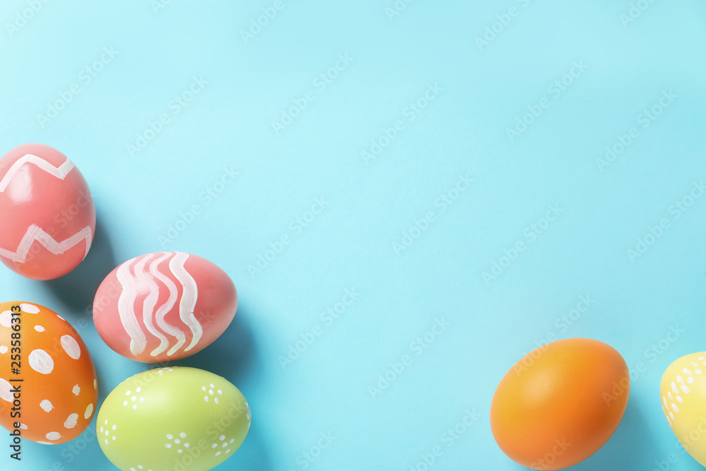 Flat lay composition of painted Easter eggs on color background, space for text