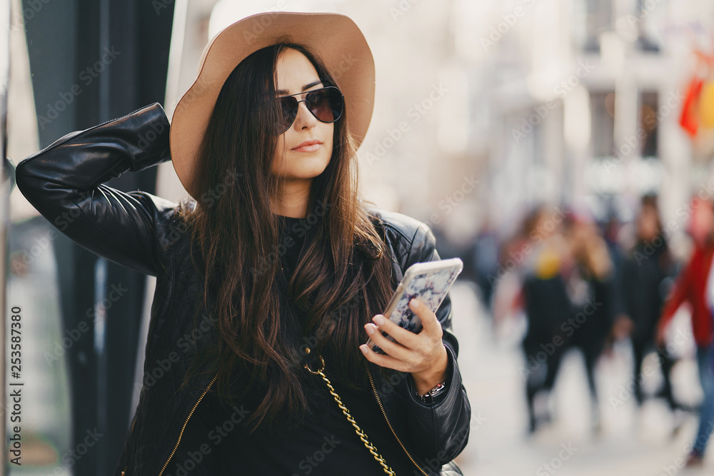 Obraz premium stylish girl in brown hat using phone in istanbul turkey