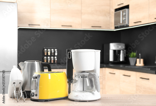 Modern domestic appliances on wooden table in kitchen. Space for text