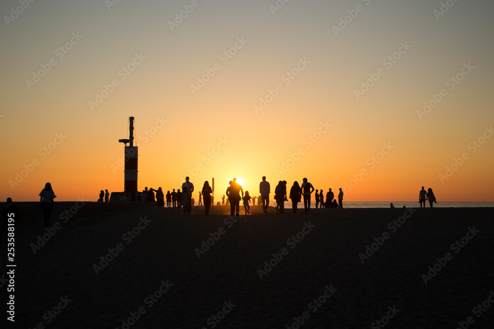 Group of people silhouette walking on the beach , with sunset backbground