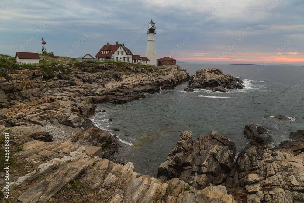 Morning sunrise at Portland Head Lighthouse over rocky coast of Portland Maine.