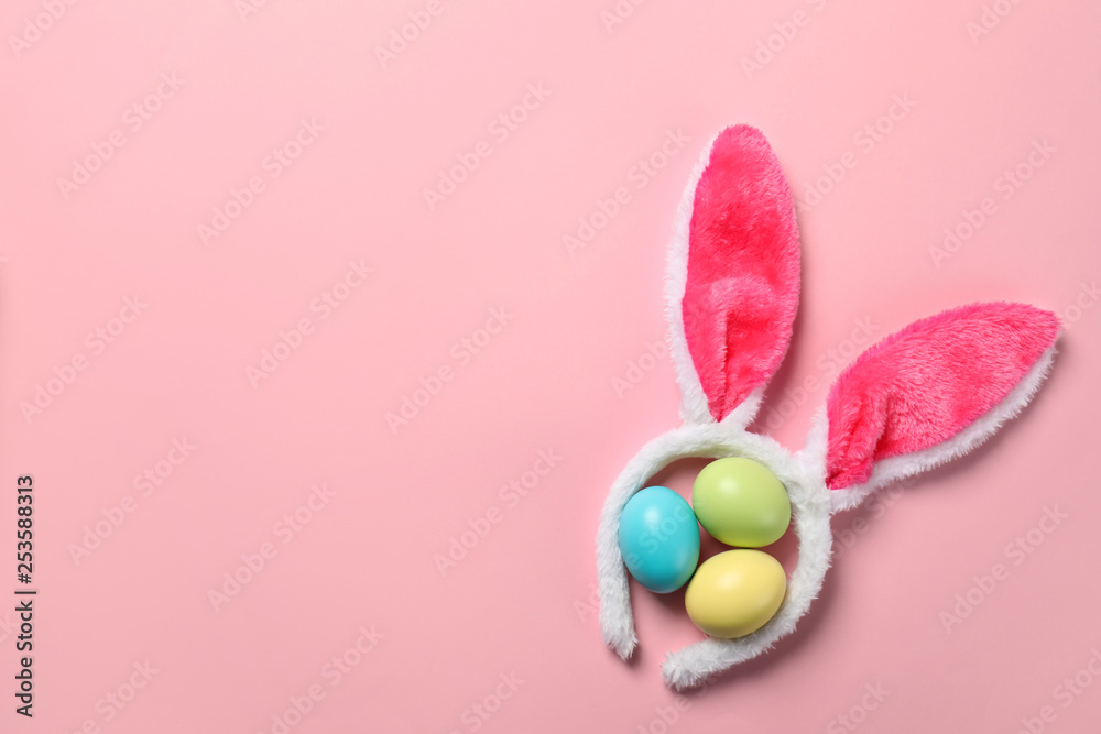 Funny headband with Easter bunny ears and dyed eggs on color background, flat lay. Space for text Funny headband with Easter bunny ears and dyed eggs on color background, flat lay. Space for text