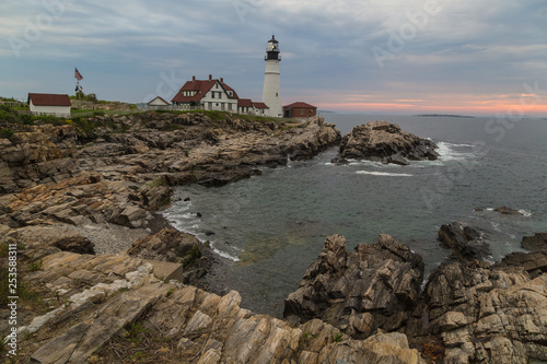 Morning sunrise at Portland Head Lighthouse over rocky coast of Portland Maine.