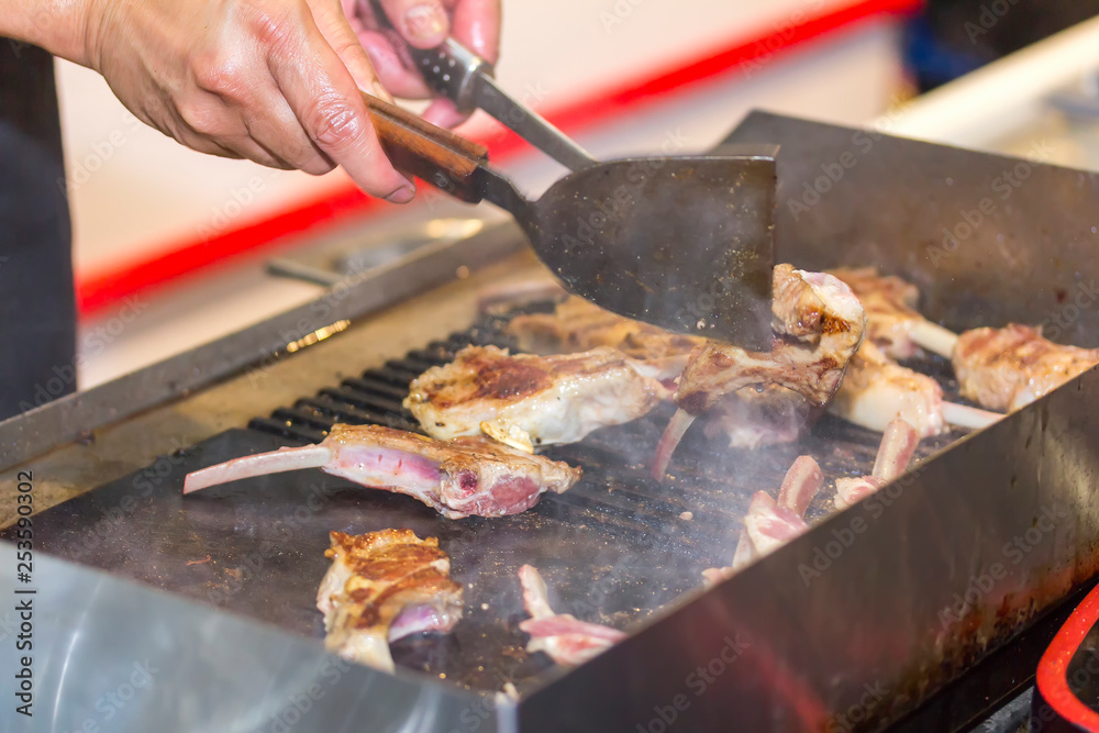 hand of man cooking delicious bone meat or barbecue steak with turner on hot pan hand of man cooking delicious bone meat or barbecue steak with turner on hot pan