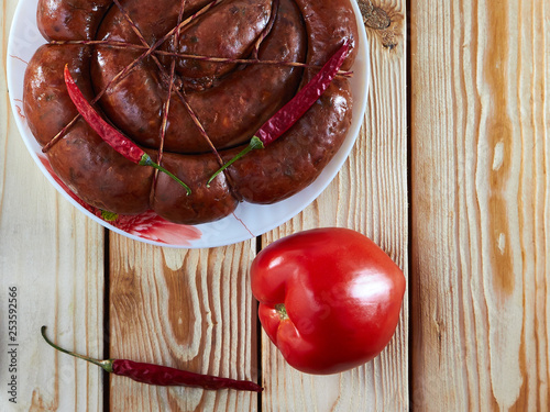 Kitchen table, on the table: smoked sausage, tomato and hot pepper to strengthen the apetite. photo