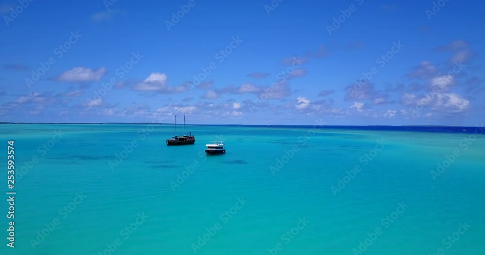 aerial view of two touristic boats anchored at a tropical island covered with palm trees, zooming in a clear day aerial view of two touristic boats anchored at a tropical island covered with palm trees, zooming in a clear day