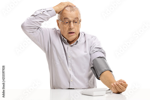 Shocked mature man taking blood pressure measurment