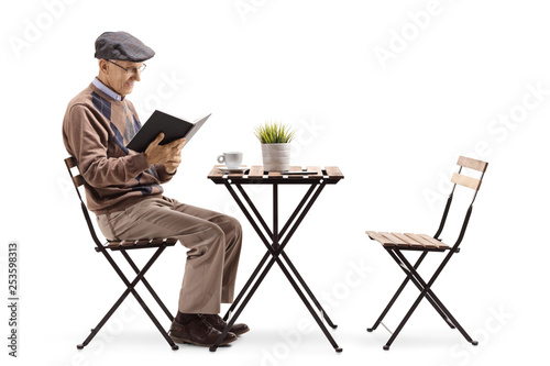 Senior man reading a book at a coffee table