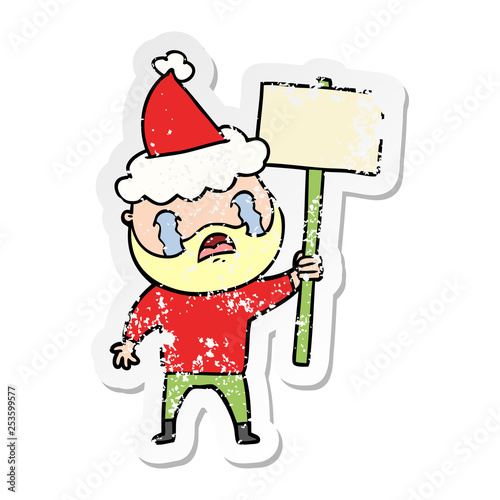distressed sticker cartoon of a bearded protester crying wearing santa hat