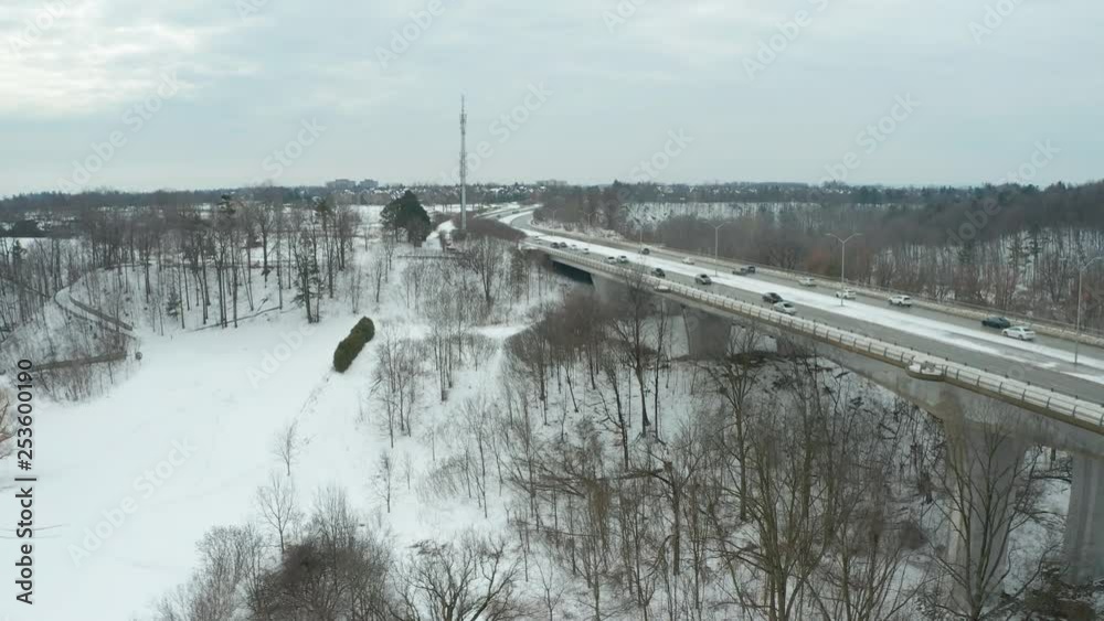 Aerial view of dozens of cars driving across a snowy bridge during wintertime Aerial view of dozens of cars driving across a snowy bridge during wintertime
