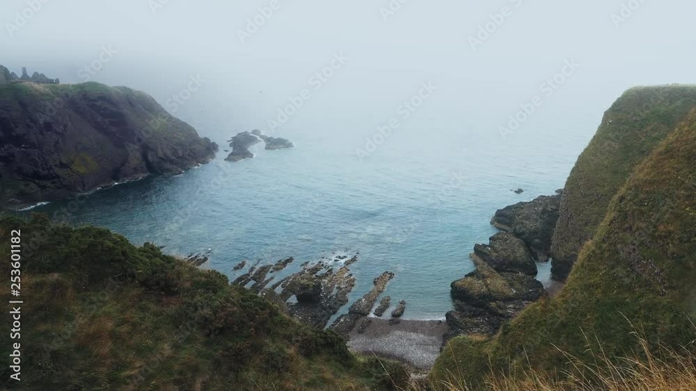 Ascending shot from a cliff edge, looking down over a rocky bay in Scotland Ascending shot from a cliff edge, looking down over a rocky bay in Scotland