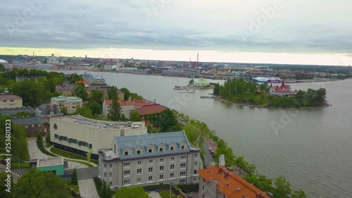 Aerial, reverse, drone shot, over buildings, in the Kaivopuisto area, the south harbor and Luoto island, in the background, on a cloudy, summer morning, in Helsinki, Finland photo