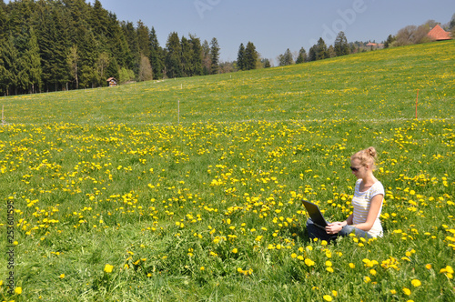 Girl with a notebook computer on the spring meadow