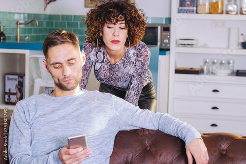 Woman spying what her boyfriend is watching on the mobile phone