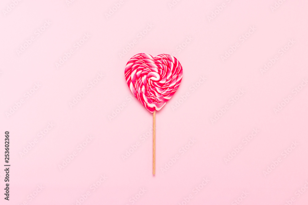 Heart shaped lollipop on a gently pink background. Flat lay, top view