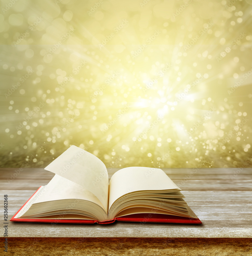 Open book on table in front of bright background Open book on table in front of bright background