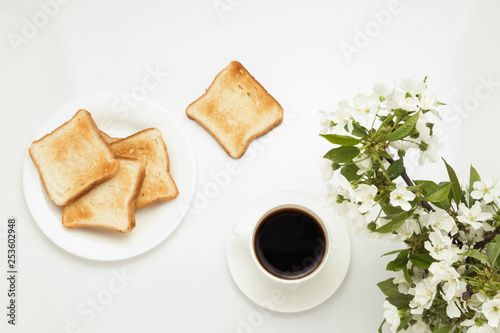 Toast, coffee and blossoming cherry branches on a white background.