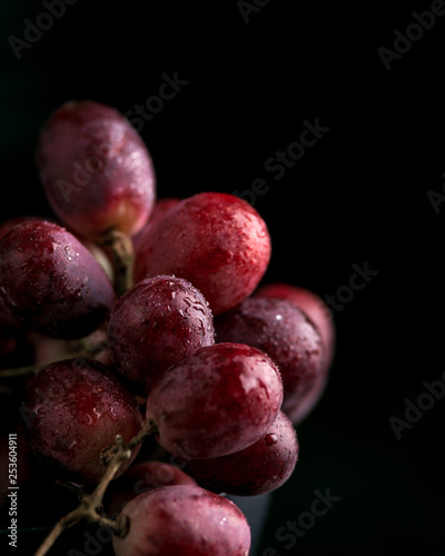 Purple grapes with water drops, grape juice in a glass jar, dark picture. Selected focus, macro.