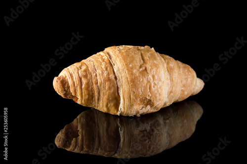 Croissant on black reflective background.