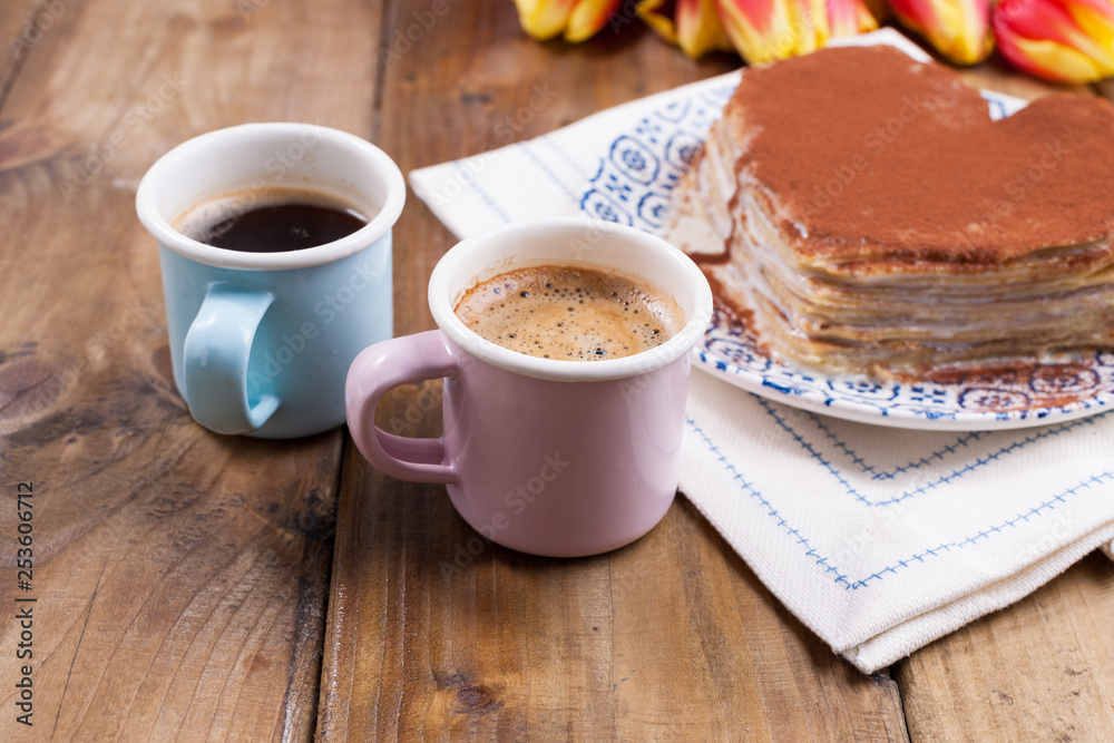 Two cups of aromatic coffee and pancakes with cream. Breakfast for two on a wooden background. Free space for text. Two cups of aromatic coffee and pancakes with cream. Breakfast for two on a wooden background. Free space for text.