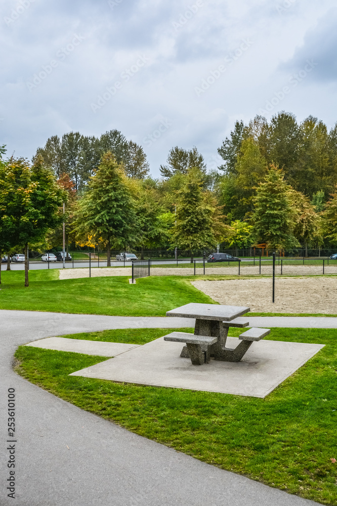Picnic table and benches on green lawn in a park