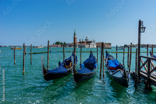 Gondolas moored by Saint Mark square with San Giorgio di Maggiore church in the background in Venice, Italy © SkandaRamana
