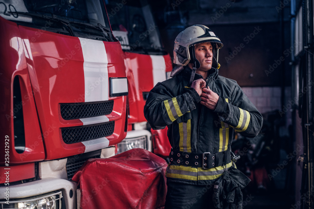 Fireman clothes protective uniforms standing next to the fire engine in the garage of a fire department Fireman clothes protective uniforms standing next to the fire engine in the garage of a fire department