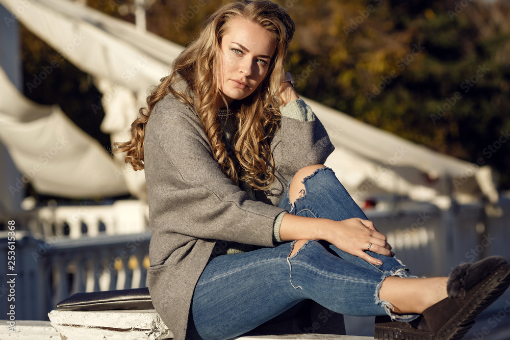 Fashion model wearing ripped boyfriend jeans, jacket and sneakers posing in the city Fashion model wearing ripped boyfriend jeans, jacket and sneakers posing in the city