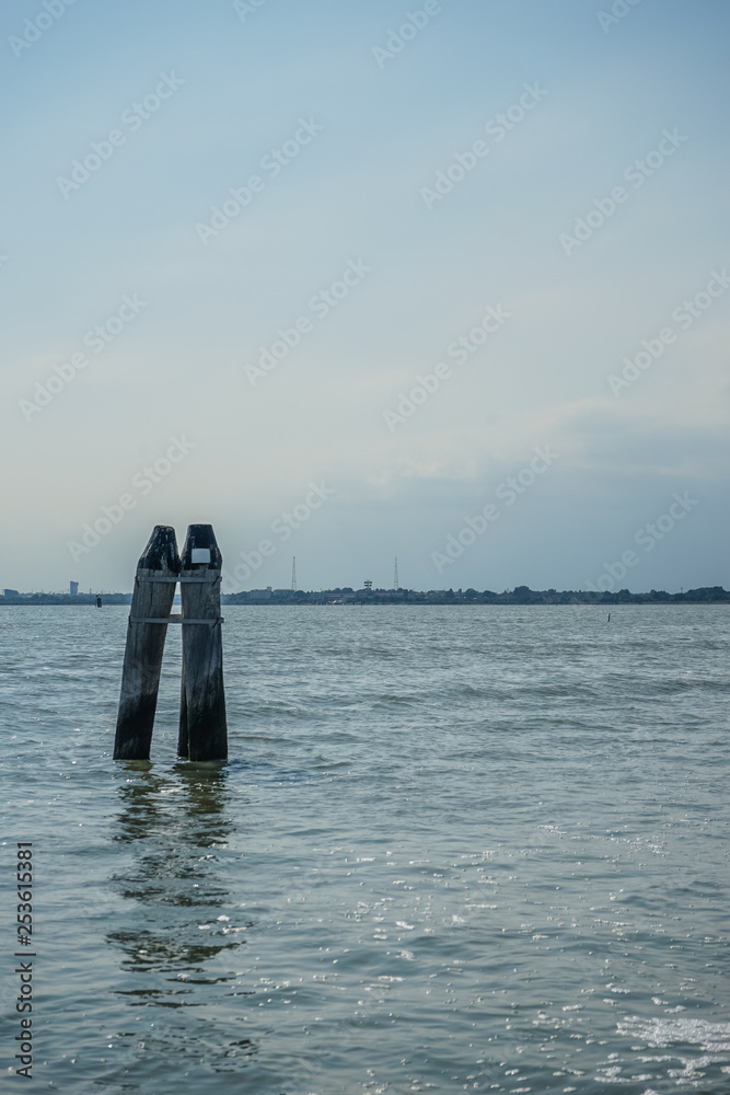 Italy, Venice, a group of wooden pikes standing next to a body of water Italy, Venice, a group of wooden pikes standing next to a body of water