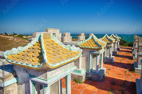 Family Tomb in the Vietnamese cemetery on the high bank on the background of the Pacific Ocean. Sunny day. Mui Ne Village, Province of Binh Thuan, Phan Thiet, Vietnam. photo