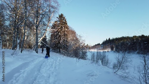 People walking in snow by frozen lake on a sunny winter day. photo