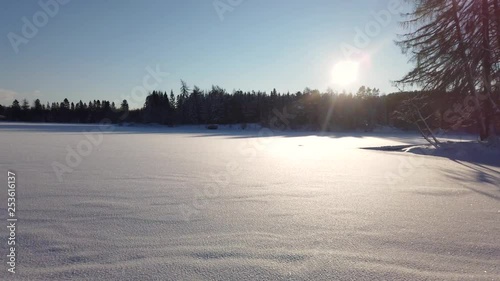 Pan over frozen lake, snow in air, sunny winter day. photo