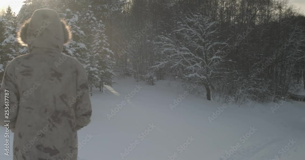 A slow panning close up shot showing a woman watching the sun as it sets over a sparkling white and beautiful rural landscape with snow covering the field and trees. A slow panning close up shot showing a woman watching the sun as it sets over a sparkling white and beautiful rural landscape with snow covering the field and trees.