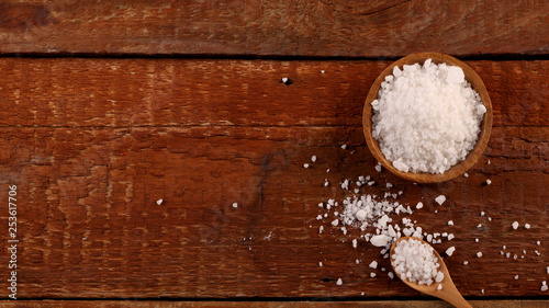 Top view of Salt or sea salt in a wooden bowl on a aged wooden table background.