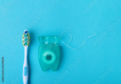 Dental floss and toothbrush on a blue background. Space for text.