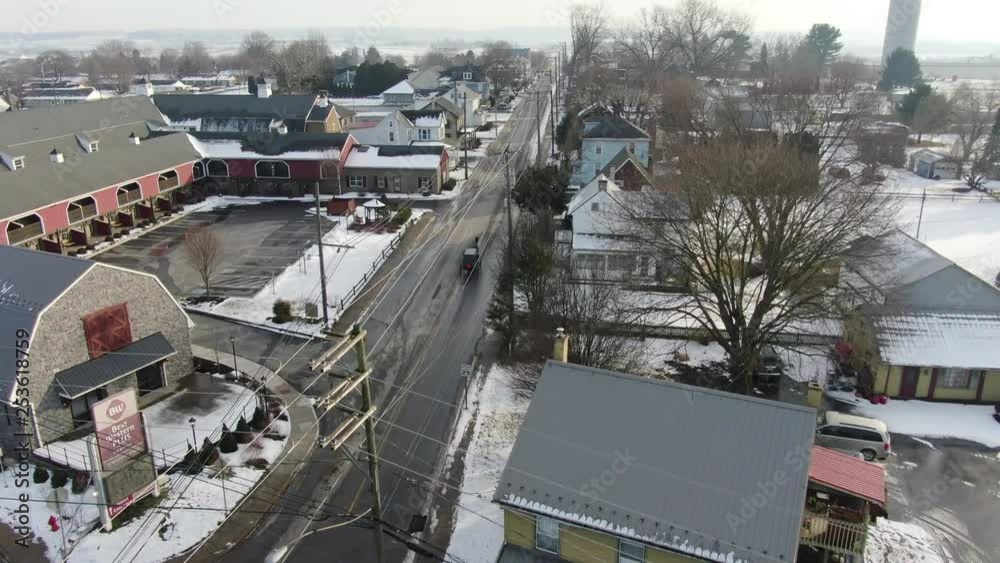 Aerial shot of rural town with Amish buggy driving through streets. Shot in Intercourse, PA in wintertime. A beautiful rural town with farms, meadows, farmlands and a small village center. Aerial shot of rural town with Amish buggy driving through streets. Shot in Intercourse, PA in wintertime. A beautiful rural town with farms, meadows, farmlands and a small village center.