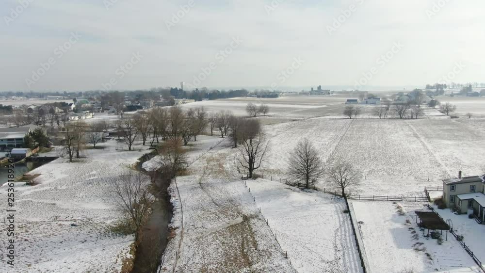 Aerial shot of beautiful snow covered rural area. Shot in Intercourse, Pennsylvania in wintertime. A beautiful snow covered rural town with farms, meadows, farmlands and a small village center. Aerial shot of beautiful snow covered rural area. Shot in Intercourse, Pennsylvania in wintertime. A beautiful snow covered rural town with farms, meadows, farmlands and a small village center.