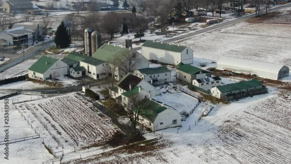 High angle aerial shot - drone circling farm in snow covered rural town. Shot in Intercourse, Pennsylvania in wintertime. A beautiful town with farms, meadows, farmlands and a small village center. High angle aerial shot - drone circling farm in snow covered rural town. Shot in Intercourse, Pennsylvania in wintertime. A beautiful town with farms, meadows, farmlands and a small village center.