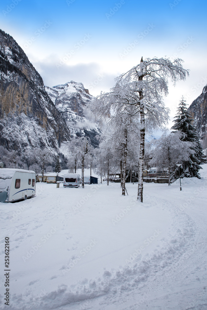 Winter camping with caravan. Camp site in the snow. Camping and travel in Switzerland. Frozen temperatures in the holiday.