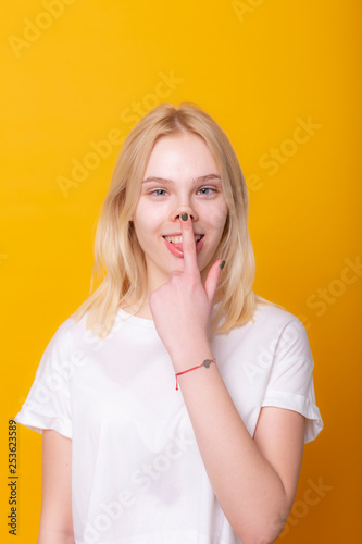 portrait of a pretty young girl in summer dress posing while standing and looking away at copy space isolated over yellow background