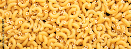 Uncooked macaroni elbow shape pasta texture background, banner photo