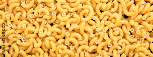 Obraz  z motywem Uncooked macaroni elbow shape pasta texture background, banner