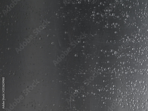 Close up rain drops on scratched aluminium metal sheet.