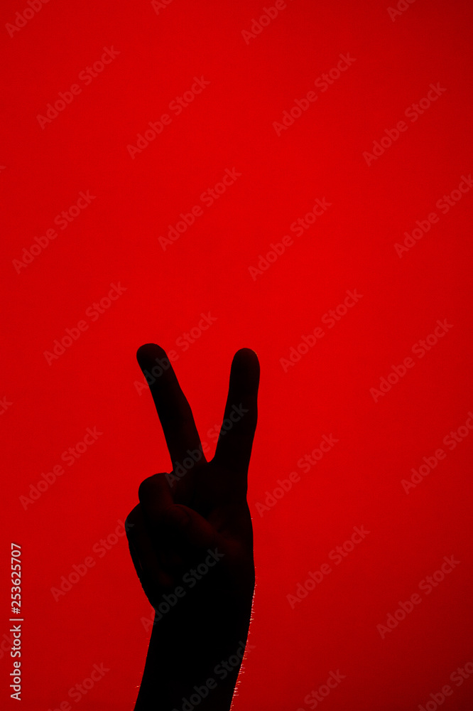 The soft hand showing the victory sign is isolated on a red background