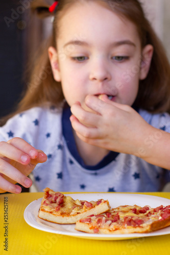 The child eats delicious pizza.