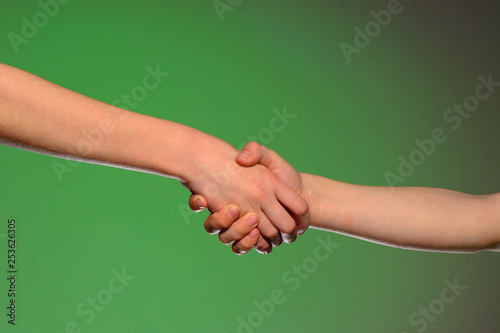 Two hands handshake, isolated on a green background, symbolizing friendship and reconciliation