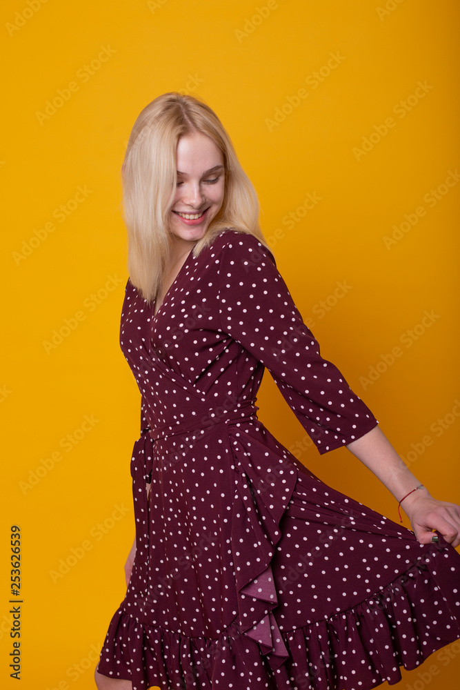a beautiful and sexy girl model posing on bright orange background for advertising casual dresses from a stylish female showroom for young, active and beautiful women. a beautiful and sexy girl model posing on bright orange background for advertising casual dresses from a stylish female showroom for young, active and beautiful women.