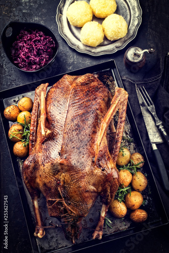 Traditional roasted stuffed Christmas duck with blue kraut and dumpling as top view on a board