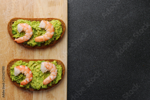shrimp and guacamole with bread on dark background